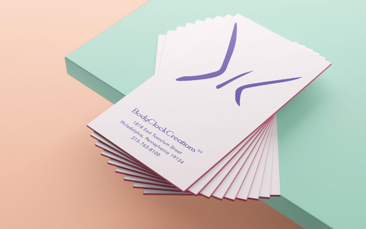 BodyClockCreations™ Business cards. Pink business cards resting on a green table.